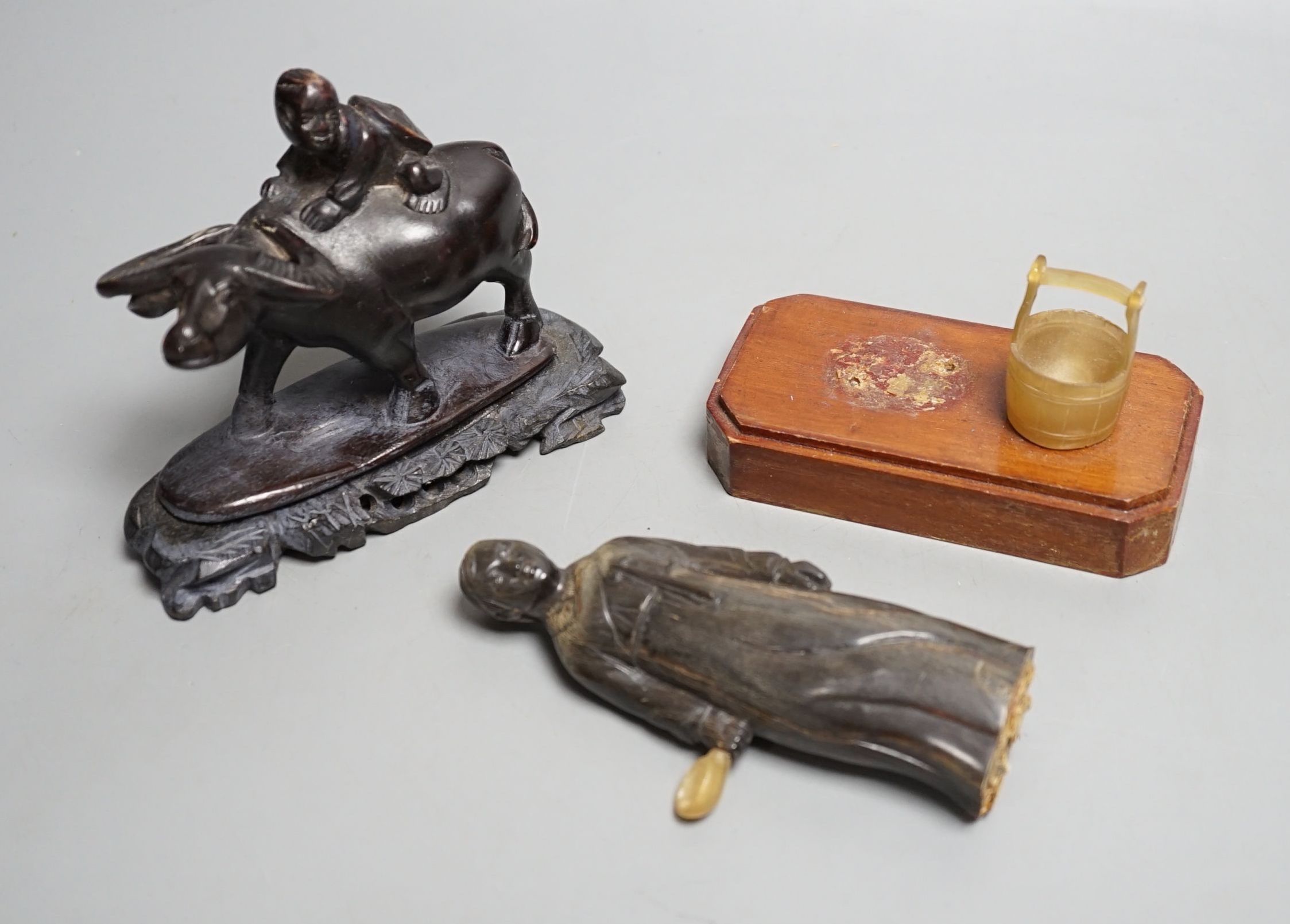 A Chinese horn figure and a carved hardwood figure riding a buffalo,13 cms wide.